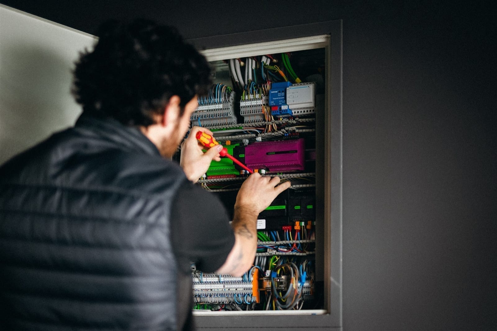 Elektryk pracujący przy rozdzielnicy z modułami automatyki w domu jednorodzinnym
